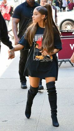 a woman walking down the street in thigh high boots and a t - shirt dress