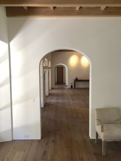 an empty room with white walls and wood flooring is seen from the hallway to the living area