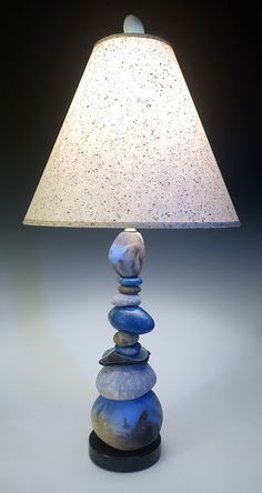 a lamp that is sitting on top of a rock stack with a white shade over it