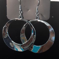 pair of silver and blue circular earrings on black surface with metal hook earwires