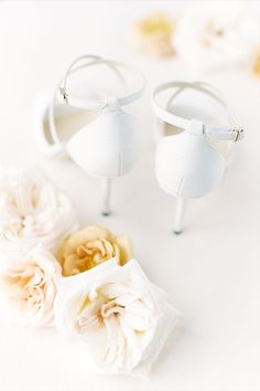 two pairs of white shoes sitting next to each other on top of a table with flowers