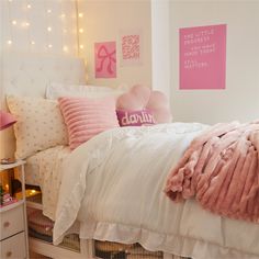 a white bed with pink pillows and blankets