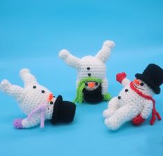 four crocheted snowmen with hats, scarves and scarfs on blue background