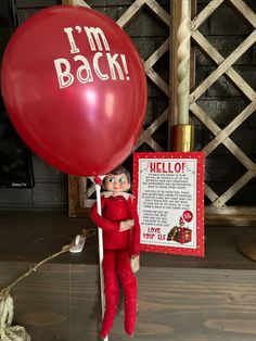 an elf holding a red balloon with the words i'm back written on it