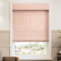 a living room with a couch, chair and window covered in pink roman blind shades