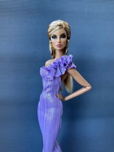 a barbie doll wearing a purple dress with ruffles