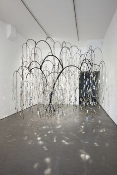 an art installation in a white room with lots of glass beads hanging from the ceiling