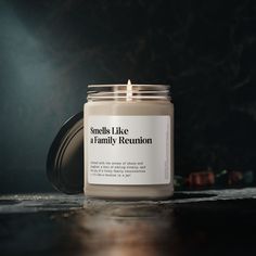 a candle sitting on top of a wooden table next to a black wall with the words smells like a family reunion written on it