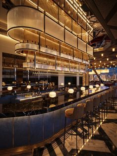 the interior of a restaurant with bar stools and lights hanging from the ceiling above