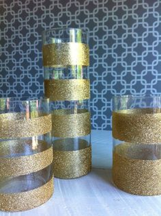 gold glitter candlesticks are stacked on top of each other in front of a patterned wall