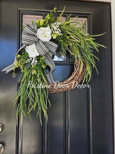 a wreath with white flowers and greenery hangs on the front door's black doors