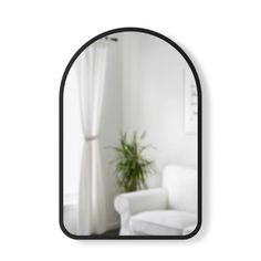 a mirror that is on the wall in front of a chair and a potted plant