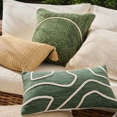 pillows on a wicker couch with green and white patterns in the backround