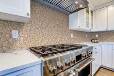 a stove top oven sitting inside of a kitchen next to white cabinets and counter tops