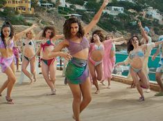 a group of women in bikinis dancing on a pier