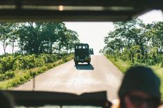 a truck driving down a road with trees in the background