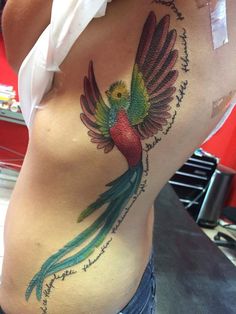 a colorful bird tattoo on the back of a woman's stomach