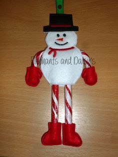 a snowman ornament hanging from a wooden table with candy canes in it