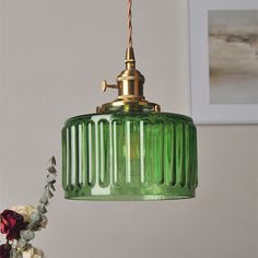 a green glass pendant light hanging from a ceiling in a living room or dining room