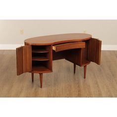 an oval shaped wooden desk with two open doors on one side and three drawers on the other