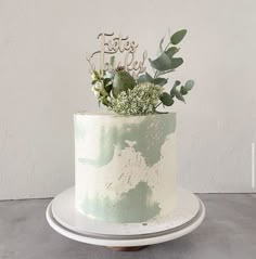 there is a white cake with greenery on top