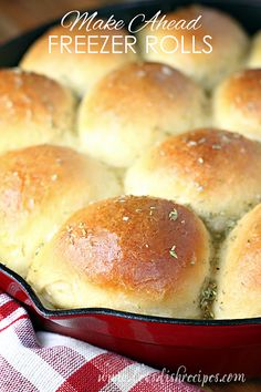 a pan filled with bread rolls sitting on top of a red and white checkered table cloth