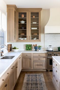 a kitchen filled with wooden cabinets and white counter tops next to a stove top oven