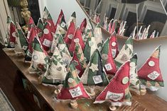 many small christmas trees are sitting on a table in front of a mirror with tags attached to them