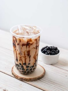 an iced drink on a wooden coaster next to a bowl of raisins