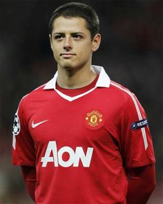 a man in a manchester united shirt standing on a soccer field