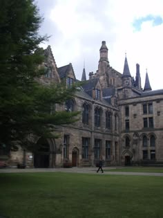 a person walking in front of a large building with many windows and towers on it