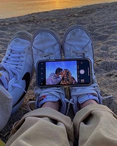 someone is taking a photo with their cell phone on the beach while they are laying down