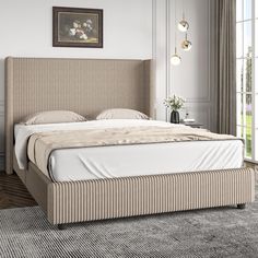 a bed with a beige headboard sitting in a bedroom next to a large window