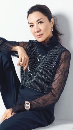 a woman sitting on top of a white bench wearing a black dress and diamond watch