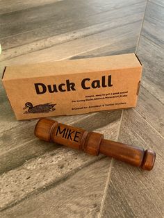 a wooden mallet sitting on the floor next to a cardboard box that says duck call