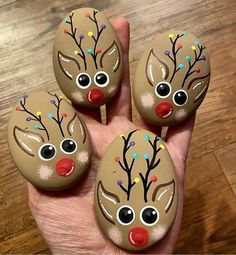 three painted rocks with reindeer faces on them in the palm of someone's hand