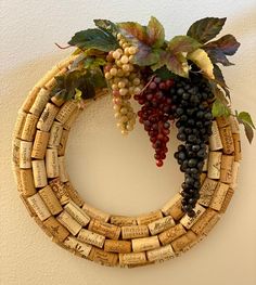 a wreath made out of wine corks with grapes and leaves hanging on the wall