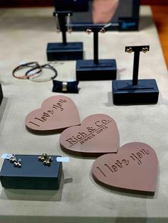 three heart shaped boxes are on display with their names written on them and two wedding rings