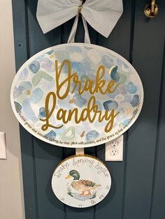 a door hanger that says, brake laundry with a duck on it and a white bow hanging from the front