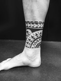 a man's leg with a black and white tattoo design on the side of his foot