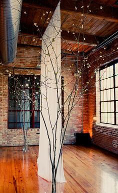 an empty room with exposed brick walls and wooden floors is decorated with white draping