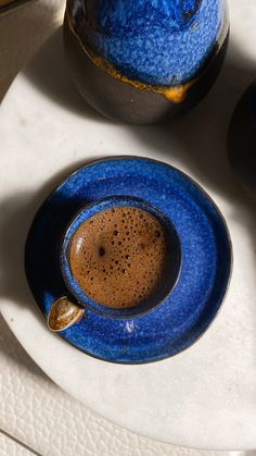 there is a blue cup and saucer on the table with an arabic quote about coffee