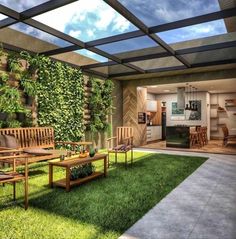 an outdoor living area with wooden furniture and green plants on the wall behind it, surrounded by grass