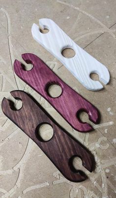 three wooden bottle openers sitting next to each other on a tile floor with holes in them