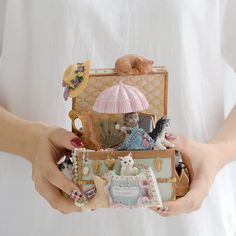 a woman is holding an open suitcase filled with figurines and other things in her hands