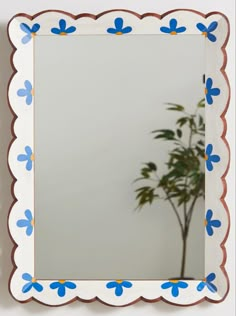 a mirror with blue flowers on it and a potted plant in the corner next to it