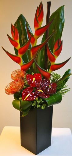 an arrangement of flowers in a black vase on a table