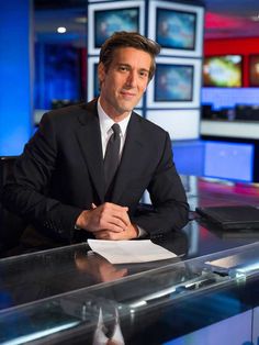 a man in a suit and tie sitting at a desk with his arms folded out