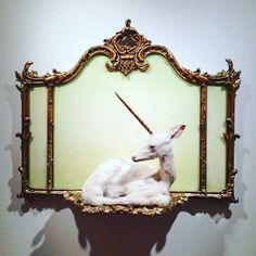 an antelope sculpture sitting on top of a table next to a wall mounted mirror