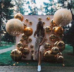 a woman sitting in front of a wall with gold balloons